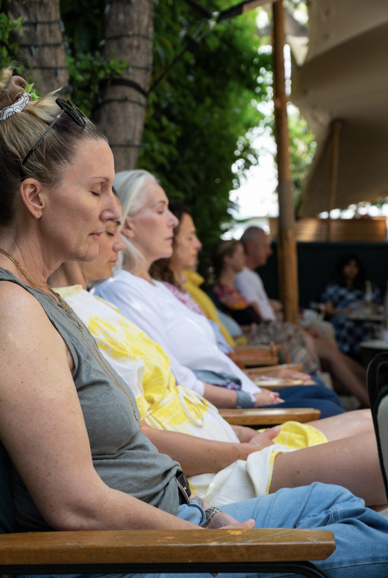 A row of participants in stillness — eyes closed, hands open