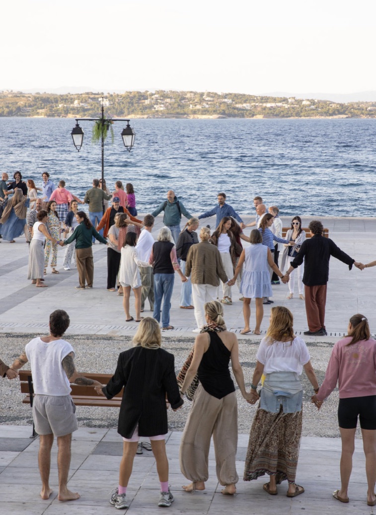 The circle holding hands on the Spetses waterfront at dusk